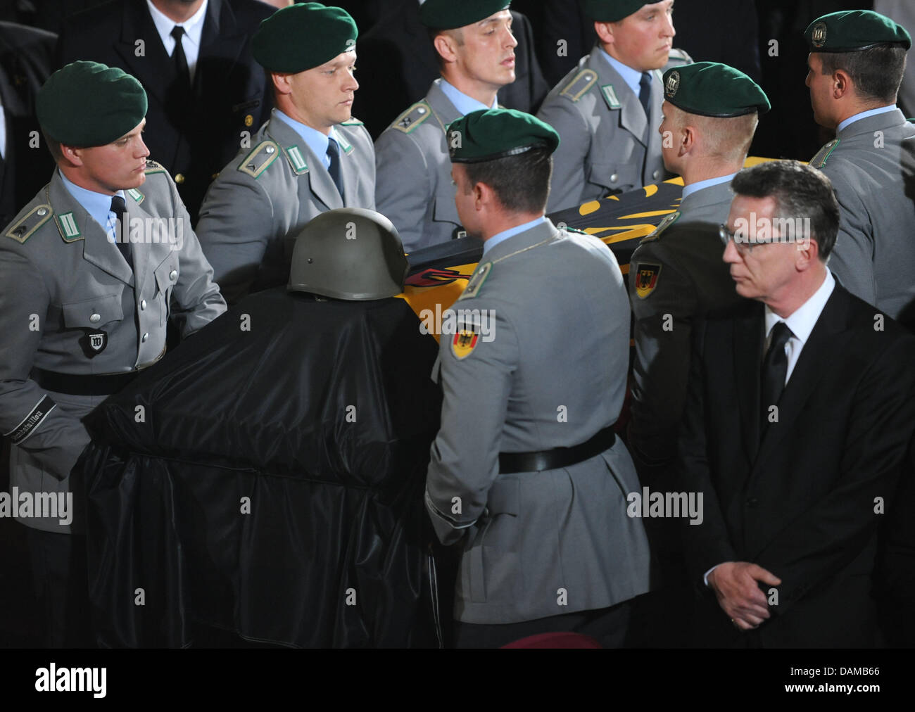 German Defence Minister Thomas de Maiziere (Front-R) steht immer noch wie die Särge von drei Soldaten der Bundeswehr, die während ihrer Mission in Afghanistan starb während einer Trauerfeier in der Epiphanias-Kirche in Hannover, 3. Juni 2011 weggetragen werden. Die Bundeswehr Abschied von den Soldaten, die während eines Angriffs in Afghanistan in der Vorwoche starb. Pho Stockfoto