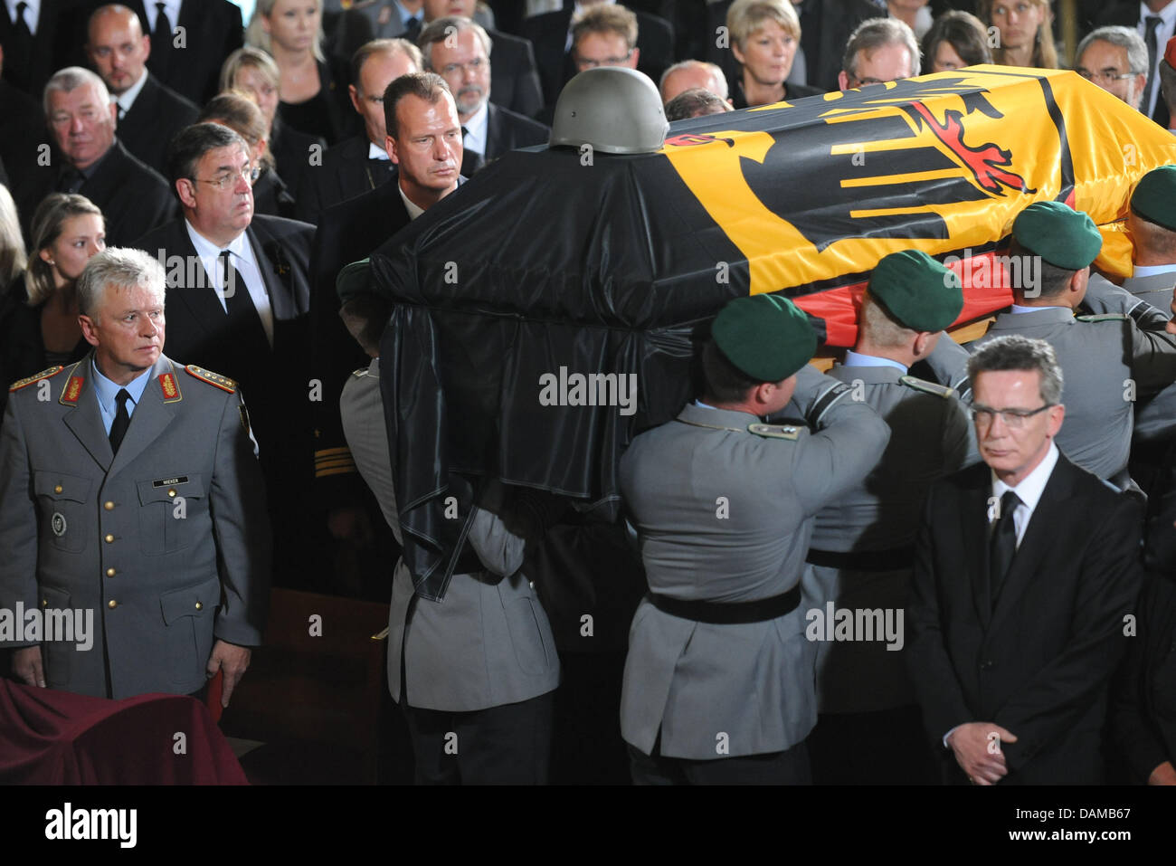 German Defence Minister Thomas de Maiziere (Front-R) steht immer noch wie die Särge von drei Soldaten der Bundeswehr, die während ihrer Mission in Afghanistan starb während einer Trauerfeier in der Epiphanias-Kirche in Hannover, 3. Juni 2011 weggetragen werden. Die Bundeswehr Abschied von den Soldaten, die während eines Angriffs in Afghanistan in der Vorwoche starb. Pho Stockfoto
