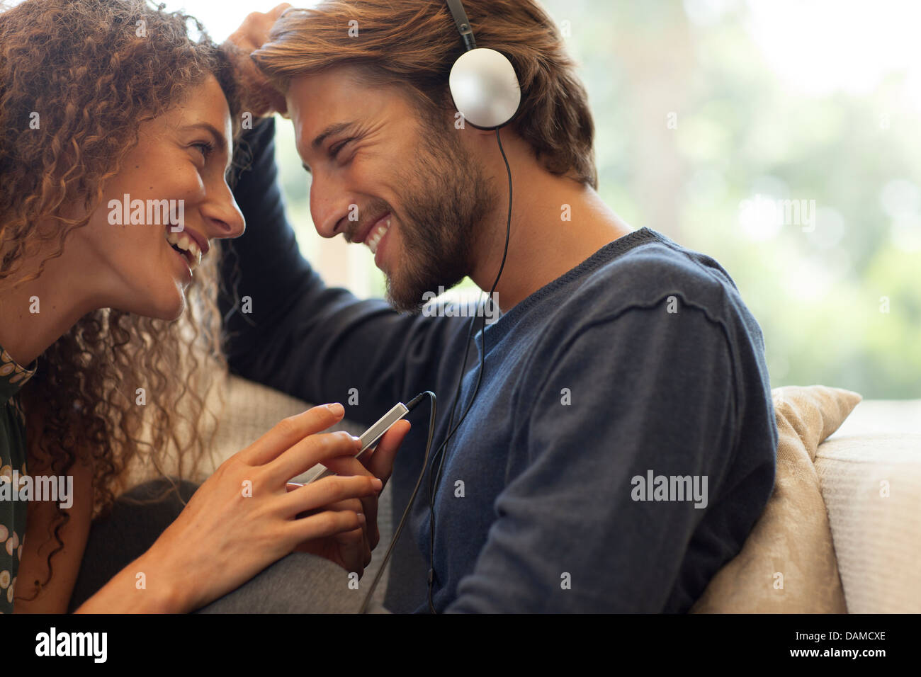 Paar, die Kopfhörer auf Sofa anhören Stockfoto