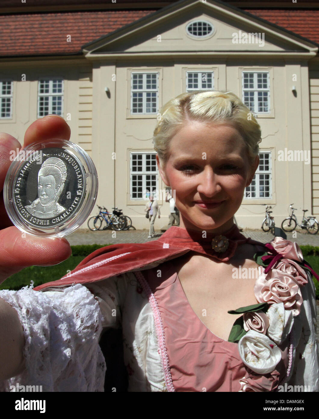 Jasmin Altmann präsentiert eine speziell geprägte Münze mit dem Bild von Königin Sophie Charlotte Zu Mecklenburg-Strelitz als ihr vor der "Drei-Königinnen-Palais" in Mirow, Deutschland, 26. Juni 2011 gekleidet. 250 Jahre nach der Krönung als britische Königin, Denk die Münze die ehemalige Prinzessin Sophie Charlotte (1744-1818) geboren in Mirow. Foto: Bernd Wuestneck Stockfoto