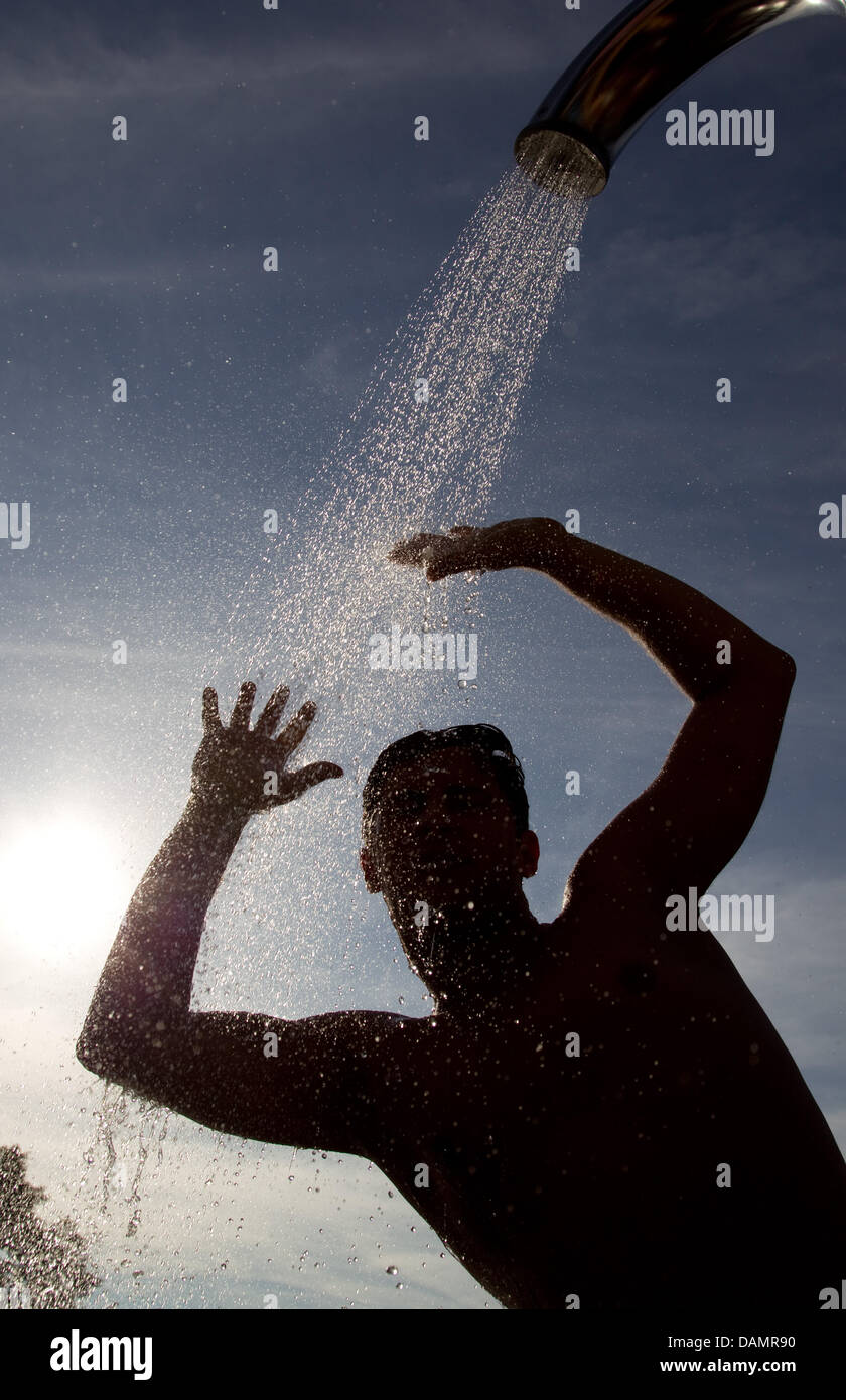 Ein junger Mann genießt eine kalte Dusche zur Abkühlung im Freibad Moskaubad in Osnabrück, 27. Juni 2011. Foto: Friso Gentsch Stockfoto
