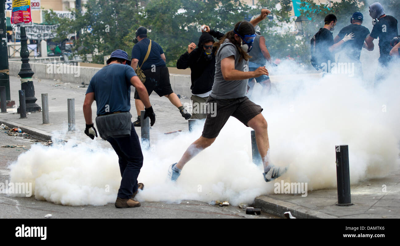 Demonstranten tragen Masken gegen Tränengas und versuchen, Weg Tränengas Granaten bei Zusammenstößen vor dem griechischen Parlament am zweiten Tag von einem 48-stündigen Generalstreik in Athen, Griechenland, Mittwoch, 29. Juni 2011 zu treten. Millionen von Griechen beteiligte sich an dem Streik zu neuen schweren Sparmaßnahmen zu widersetzen, die Teil eines Rahmens mittelfristige finanzpolitische Strategie 2012-2015 sind con werden soll Stockfoto