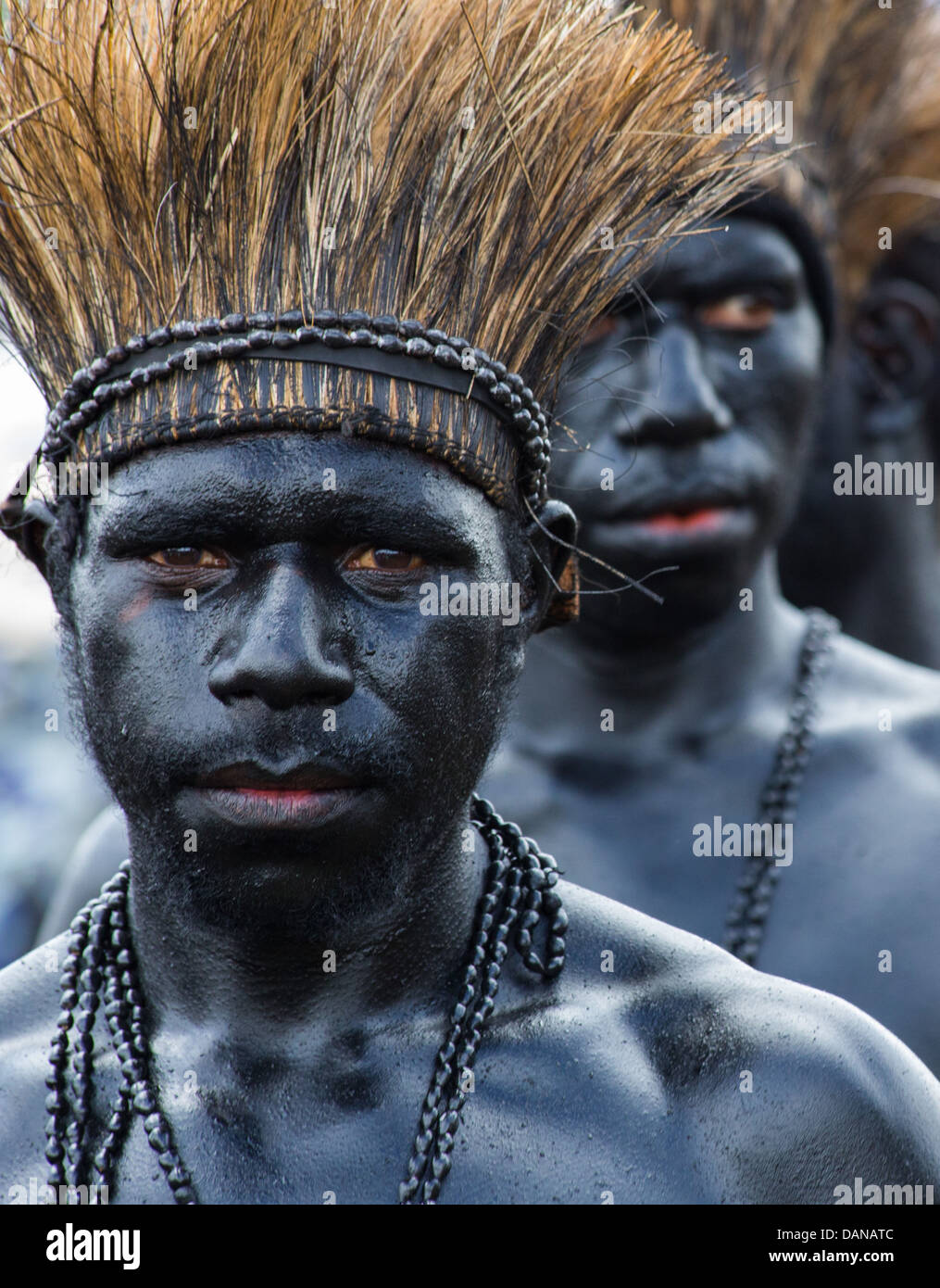 Stammes-Männer lackiert glänzend schwarz und tragen Rasen Kopfschmuck auf dem Goroka Festival in Papua-Neu-Guinea Stockfoto