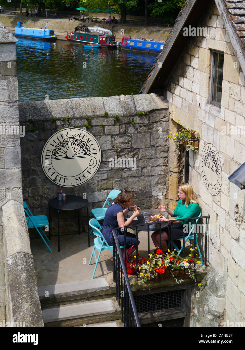 Zwei Frauen sitzen Sie draußen ein Café neben dem Fluss Ouse mit Kanalboote, York, England. Stockfoto