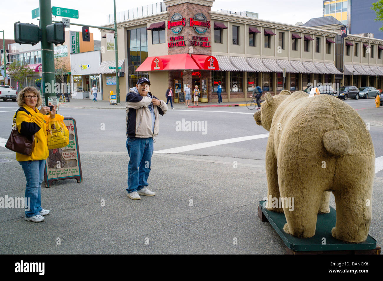 Touristen fotografieren einen gefälschten Grizzly-Bären auf dem Bürgersteig, Anchorage, Alaska, USA Stockfoto