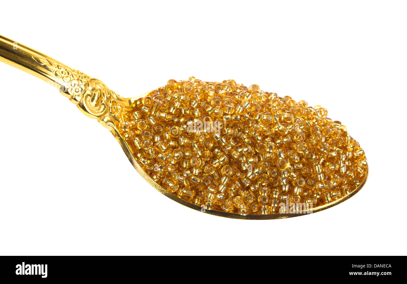 Ein goldener Löffel gefüllt mit gold Glasperlen. Stockfoto