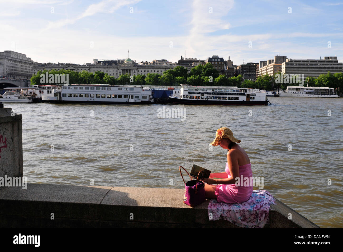 Eine Frau liest ein Buch am Südufer der Themse, London Stockfoto