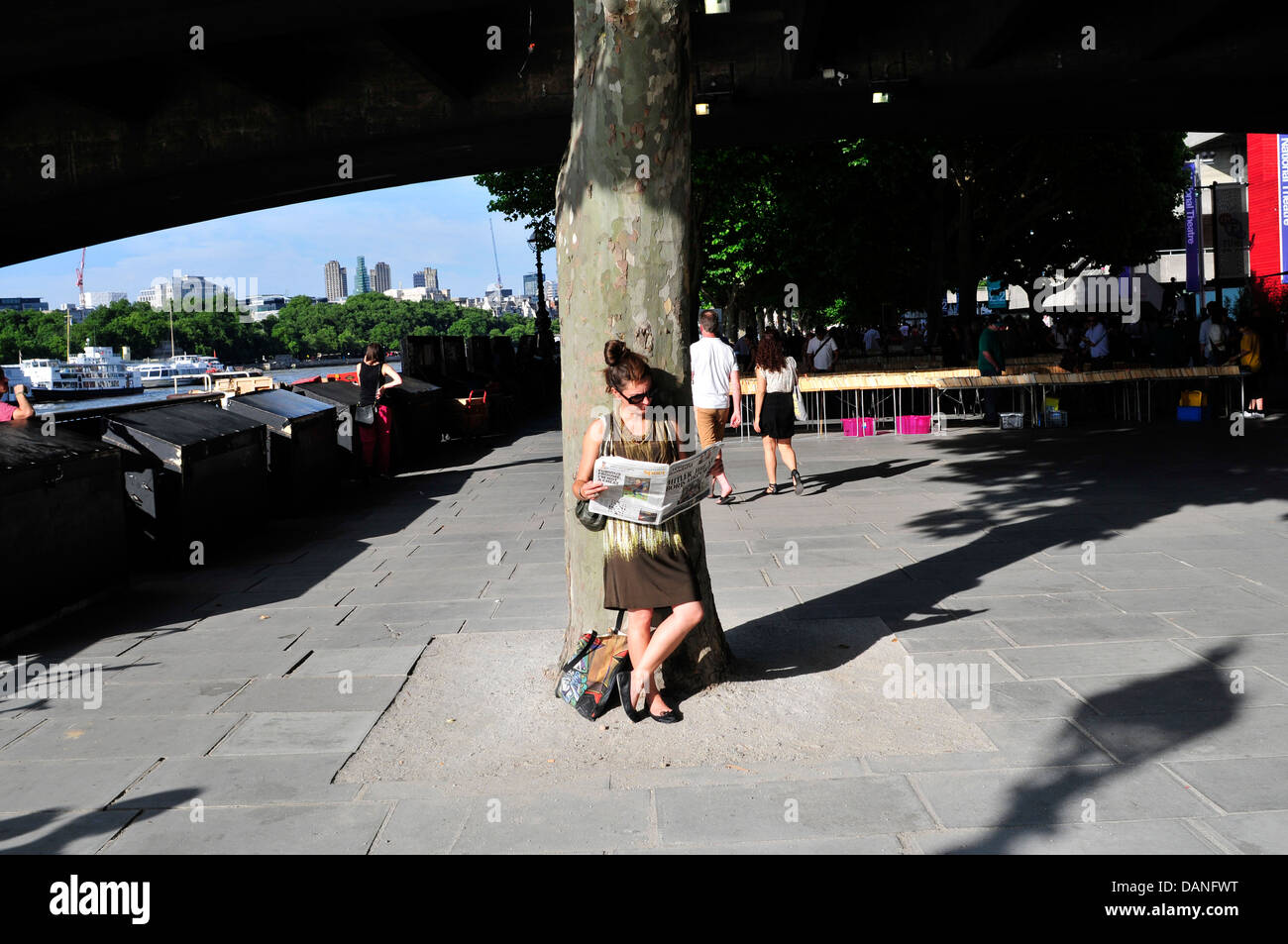 Eine Frau liest eine Zeitung, South Bank, London, UK Stockfoto