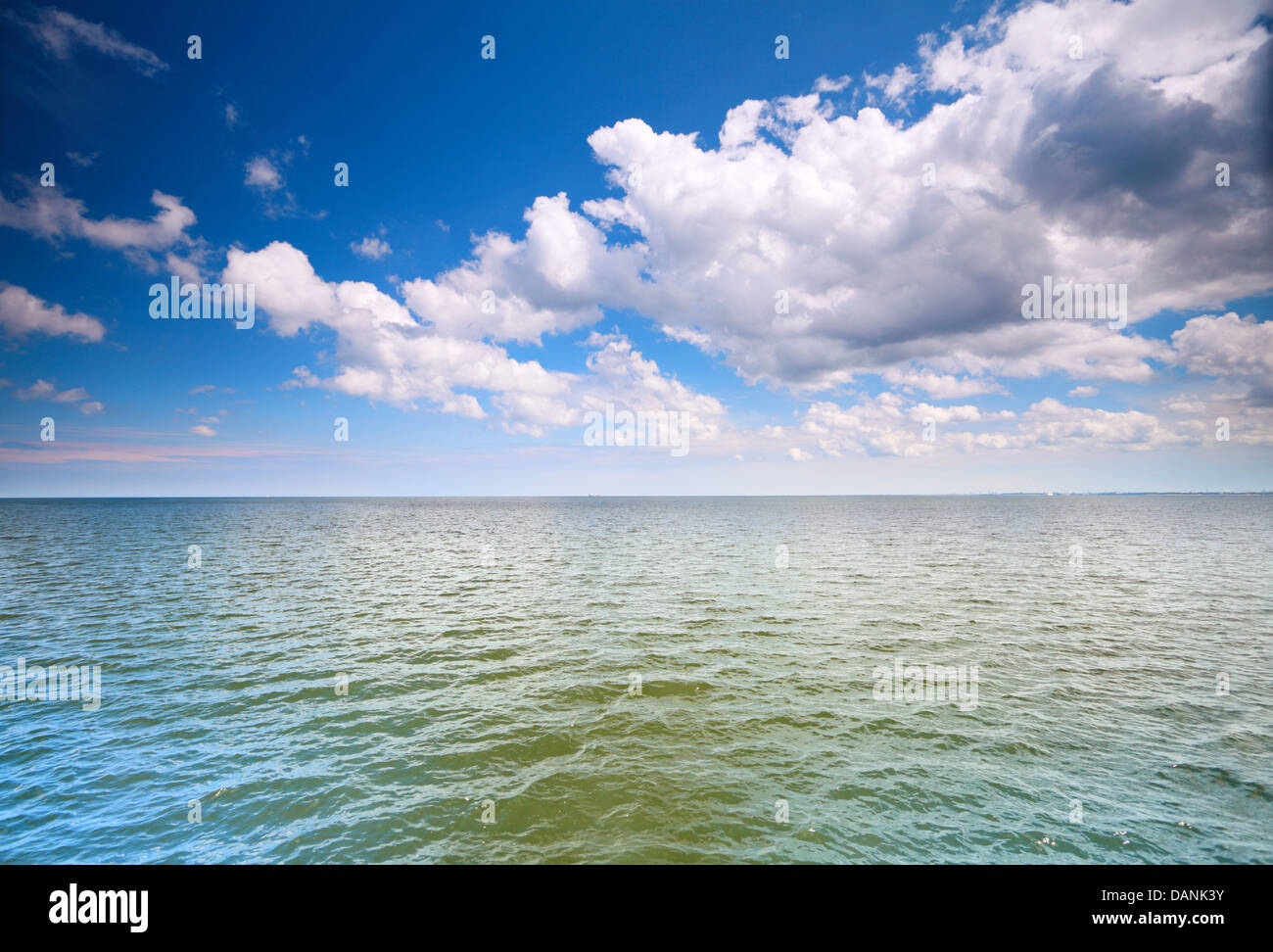 Weiße flauschige Wolken blauer Himmel über einer Oberfläche des Meeres Stockfoto
