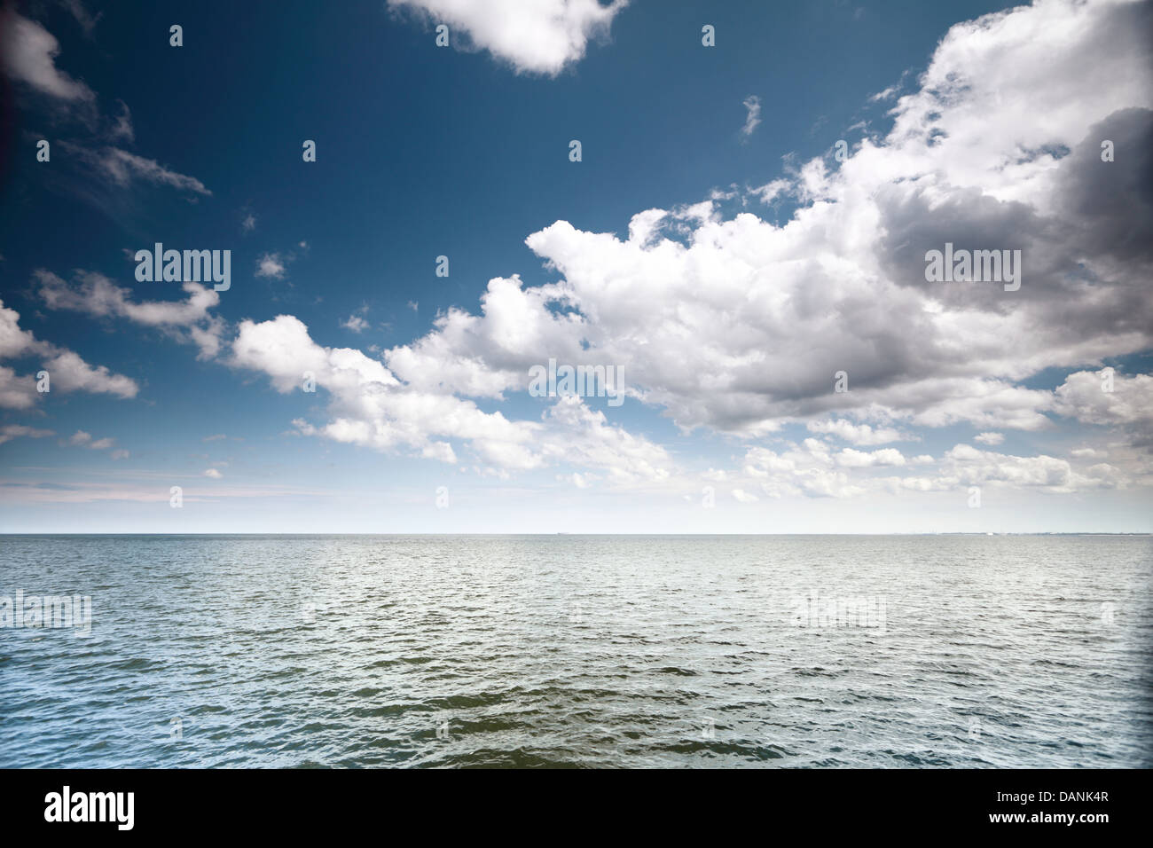 Weiße flauschige Wolken blauer Himmel über einer Oberfläche des Meeres Stockfoto