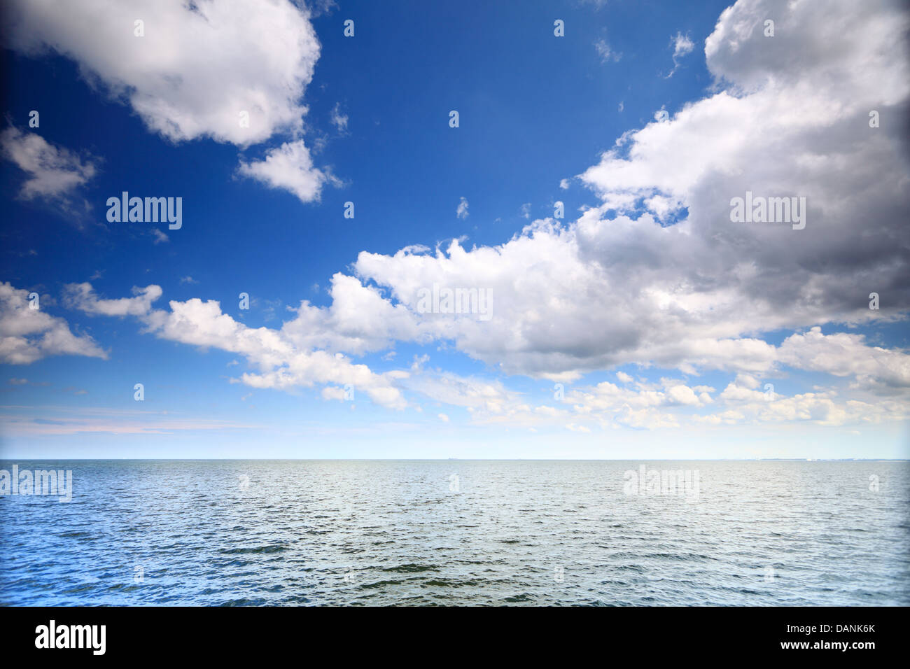 Weiße flauschige Wolken blauer Himmel über einer Oberfläche des Meeres Stockfoto