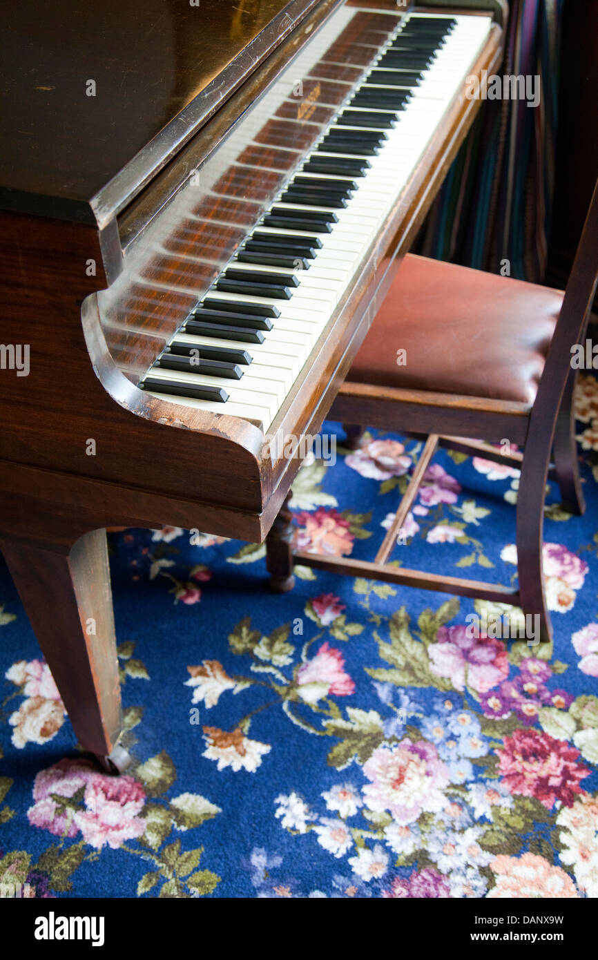 Klavier und Stuhl auf traditionellen Blumenteppich Stockfoto