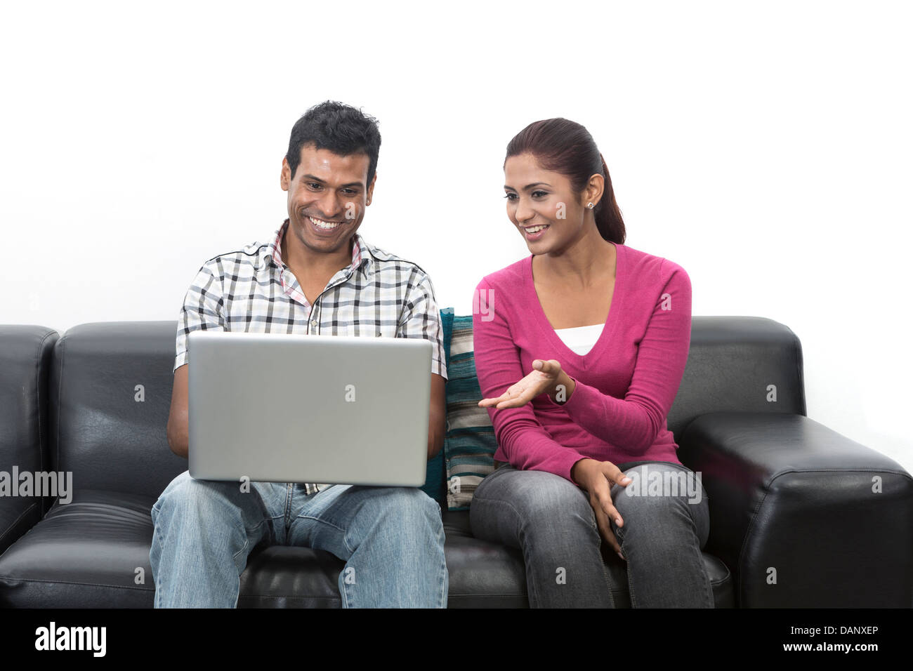 Indische Paare entspannen auf dem Sofa mit einem Laptop in ihrem Wohnzimmer zu Hause Stockfoto