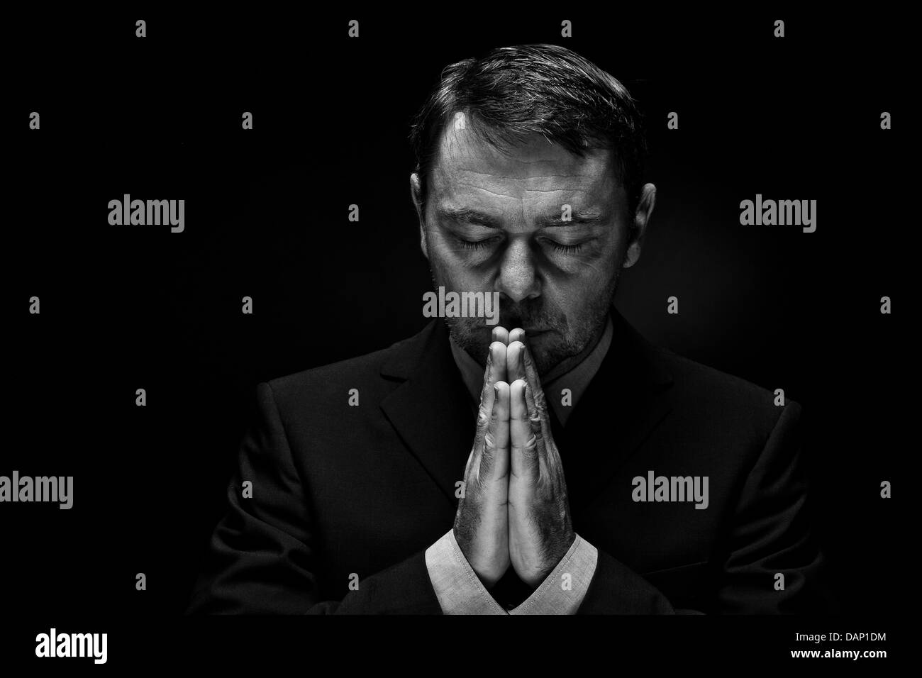 Reifen Mann in vollständigen Anzug beten vor schwarzem Hintergrund, Nahaufnahme Stockfoto