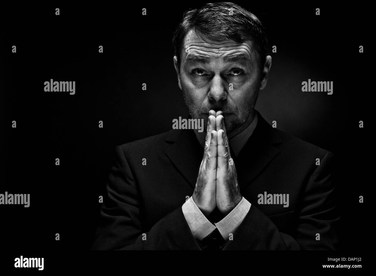 Reifen Mann in vollständigen Anzug beten vor schwarzem Hintergrund, Nahaufnahme Stockfoto