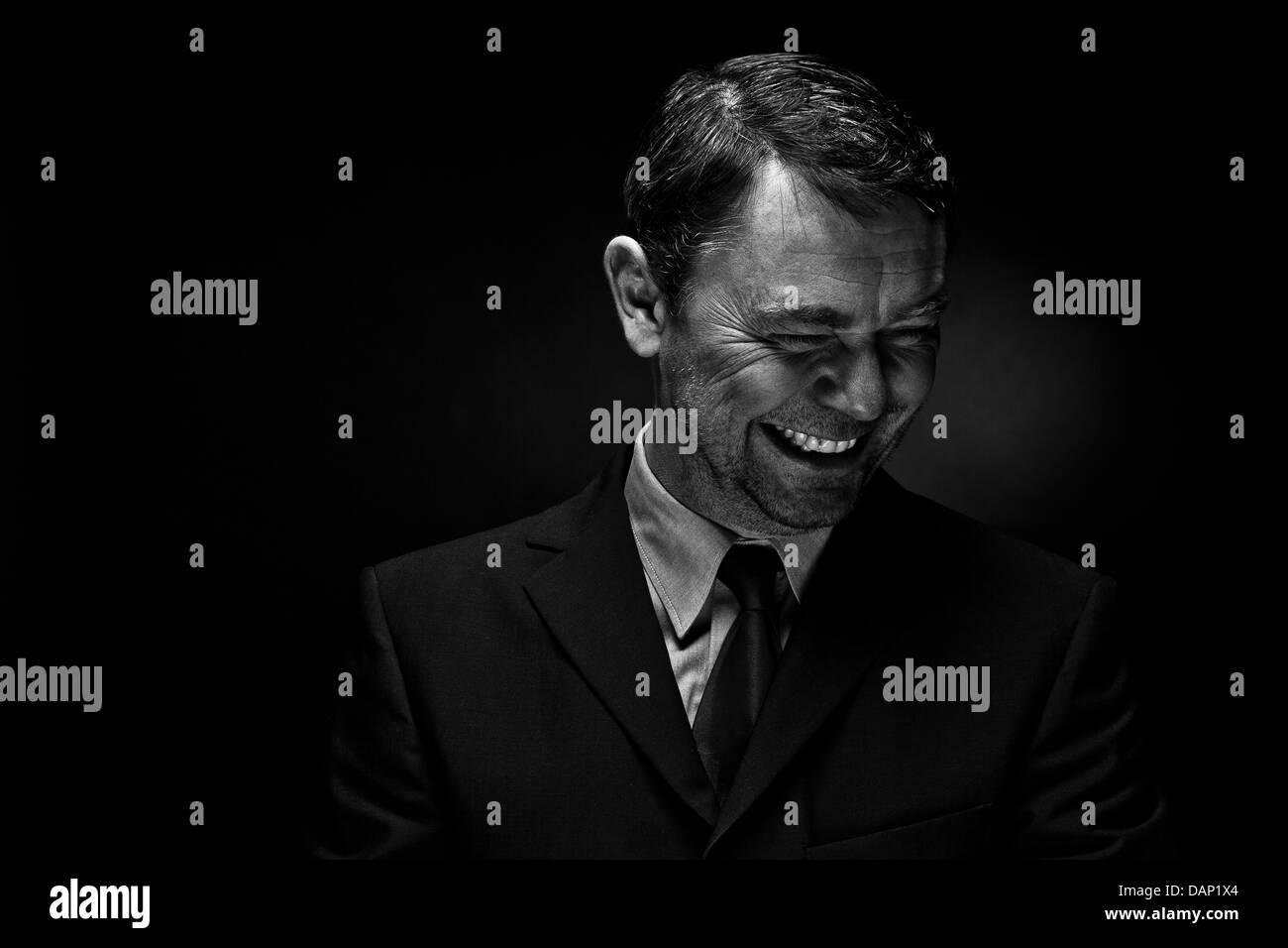 Reifer Mann lächelnd vor schwarzem Hintergrund Stockfoto