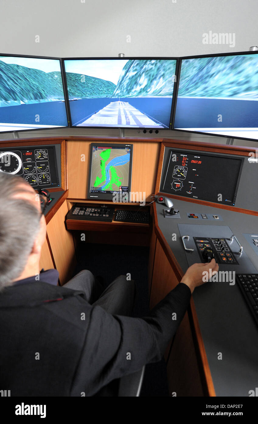 Ein Mann navigiert in einem Schiff-Handling Simulator am Bundes Wasserstraßen Engineering and Research Institute in Karlsruhe, Deutschland, 20. Juli 2011. Der Schiff-Handling-Simulator wird derzeit verwendet, um den Unfall der angetriebenen Tanker Waldhof auf dem Rhein bei St. Goarshausen im Januar 2011 zu simulieren. Die Bildschirme zeigen die ungefähre Szene des Unfalls in der Nähe der Loreley Stockfoto