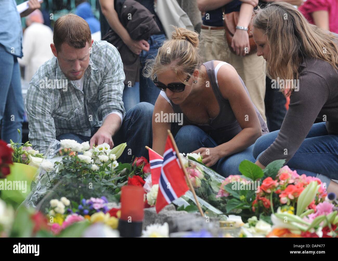 Menschen legen Blumen vor der Kathedrale von Oslo zu respektieren, den getöteten am 22 Juli Zeltlager schießen Spree auf der Insel Utoya, westlich der Hauptstadt Oslo und Opfer von der gleichzeitigen Bombenanschlag in Oslo, Norwegen, 23. Juli 2011. Ein norwegischer Mann angeklagt war 23 Juli zwei Attentaten, die behauptet, dass mindestens 91 22 Juli lebt, teilte die Polizei mit. Der 32-j hrige war arres Stockfoto