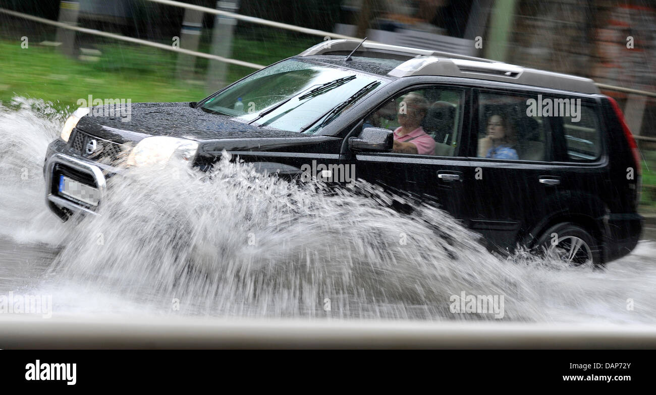 Ein Auto fährt durch eine überschwemmte Straße in Bochum, Deutschland, 28. Juli 2011. Foto: MARIUS BECKER Stockfoto