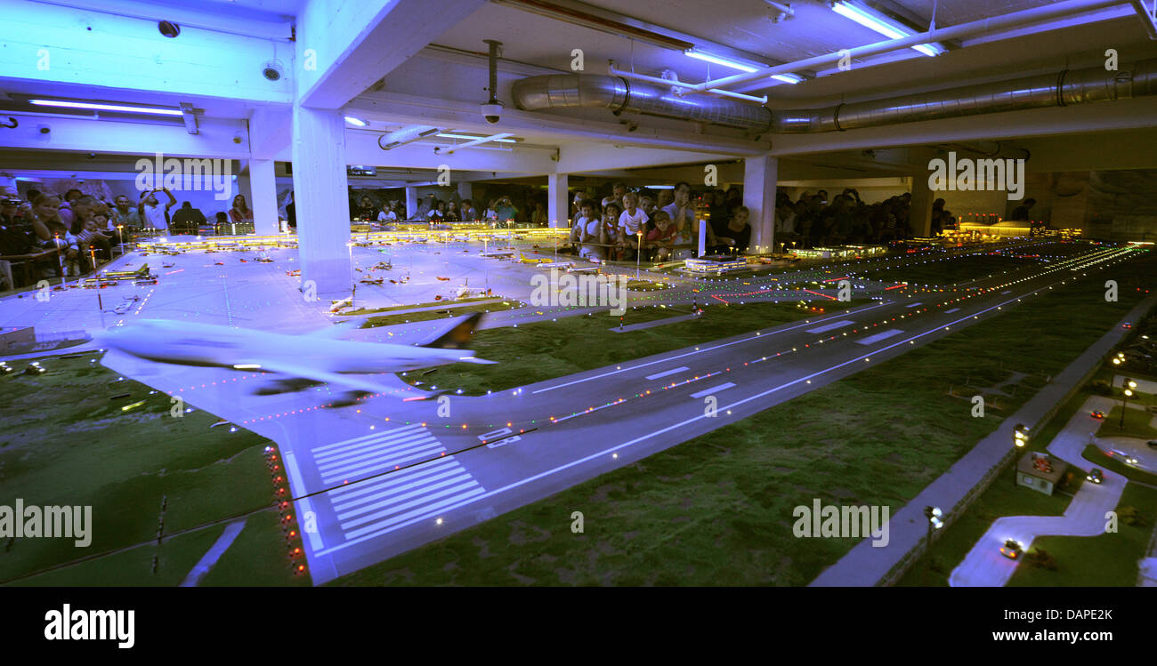 Besucher betrachten "Flughafeneröffnung" Flughafen in der Modelleisenbahn Miniatur Wunderland in Hamburg, Deutschland, 12. August 2011. Miniatur Wunderland feiert sein 10-jähriges Jubiläum am Dienstag. Seit seiner Eröffnung am 16. August 2001 kommen rund 8,3 Millionen Besuchern die größte Modelleisenbahn der Welt zu sehen. Foto: Christian Charisius Stockfoto