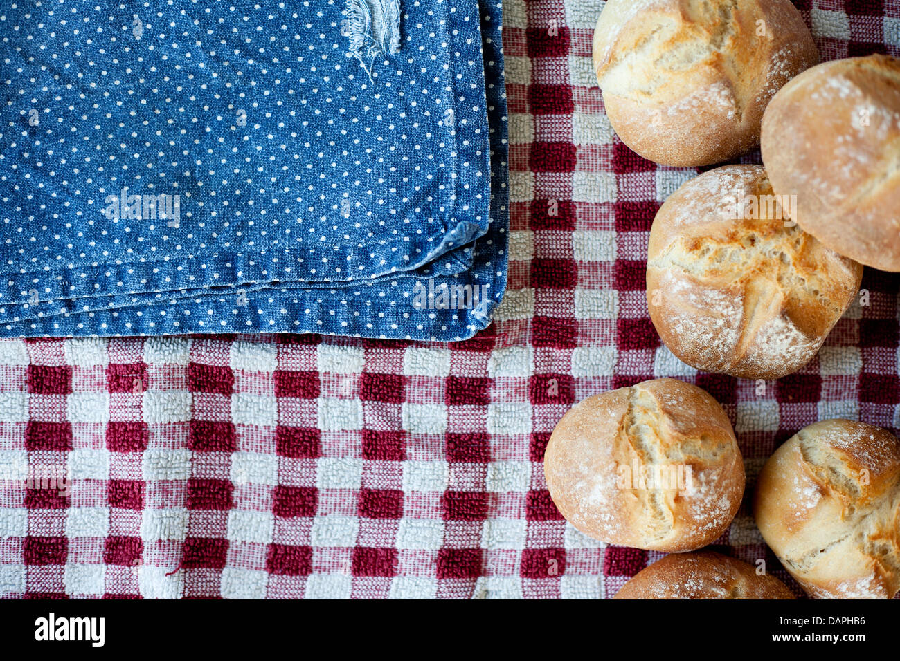 Knuspriges, rustikale Brötchen, Hause gebacken, frisch aus dem Ofen. Blaues und rotes Tuch, Top-down Ansicht, geringe Schärfentiefe. Stockfoto