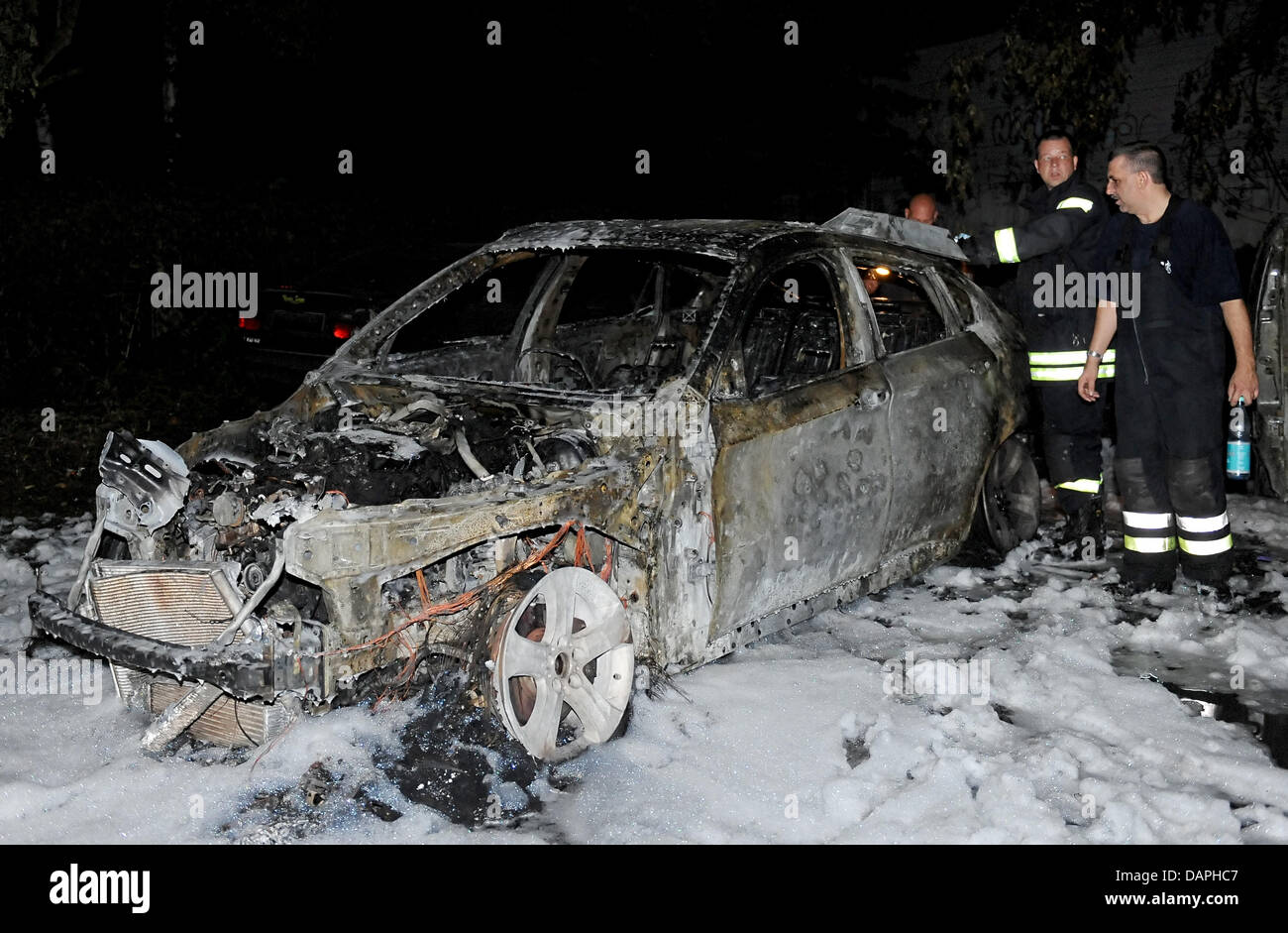 Feuerwehr Scannen eine verbrannte Fahrzeug auf einem Parkplatz an der Hochstrasse in Berlin-Wedding, Deutschland, 22. August 2011. Eine Woche lang brennen Autos in der deutschen Hauptstadt in der Nacht. Rund 80 Fahrzeuge sind mittlerweile ganz oder teilweise beschädigt. Foto: Britta Pedersen Stockfoto