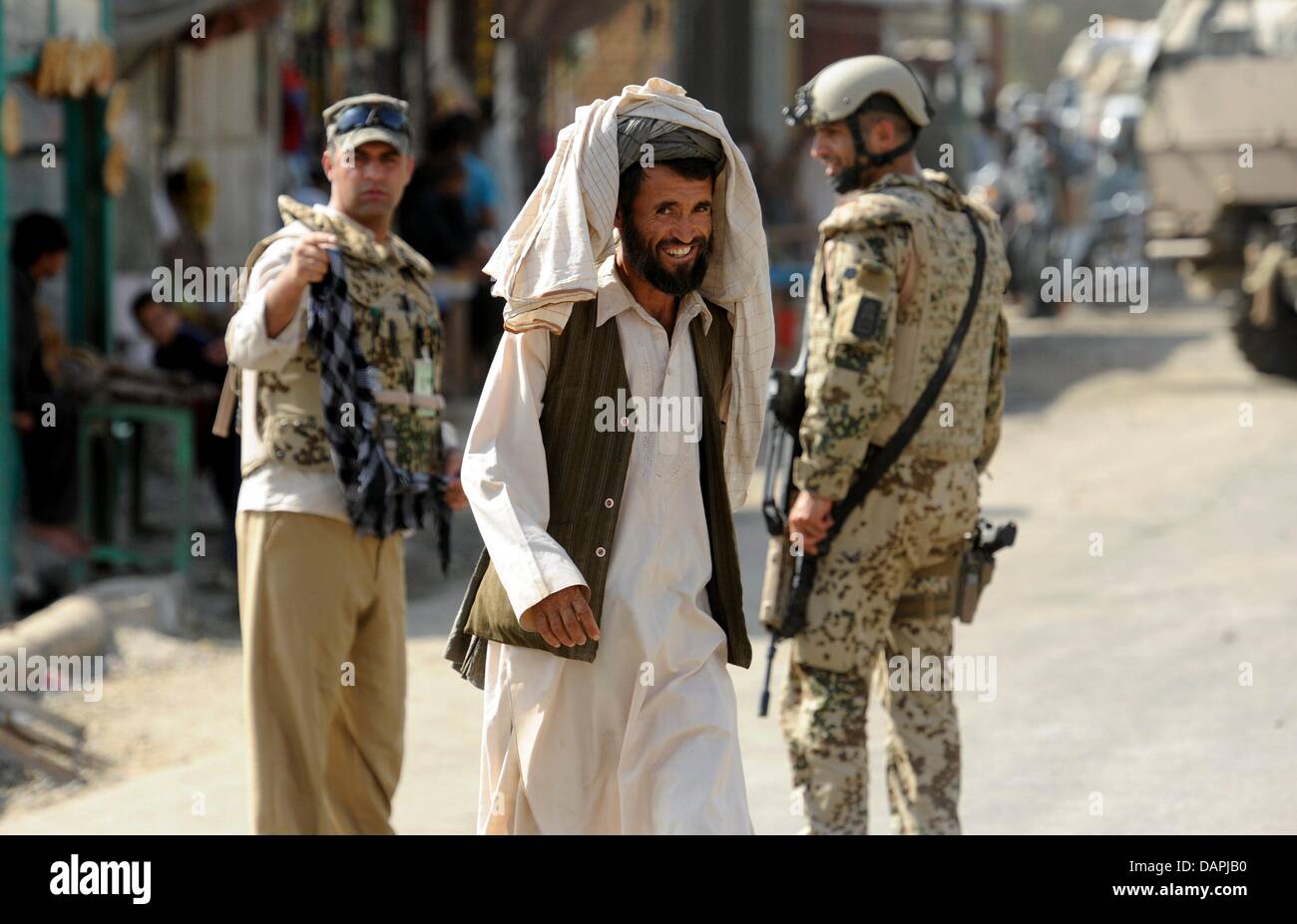 Ein afghanischer Mann herein übergebenen Bundeswehr Soldat Khanabad in Kunduz, Afghanistan, 23. August 2011. Sie blockiert hatte die Website einer hausgemachten Bombe, die von unbekannten Personen auf der Straße zu den Polizeichef Haus begraben wurde entdeckt. Afghanistan-Sicherheits- und Polizeikräfte werden immer wieder von den Taliban angegriffen. Foto: MAURIZIO GAMBARINI Stockfoto