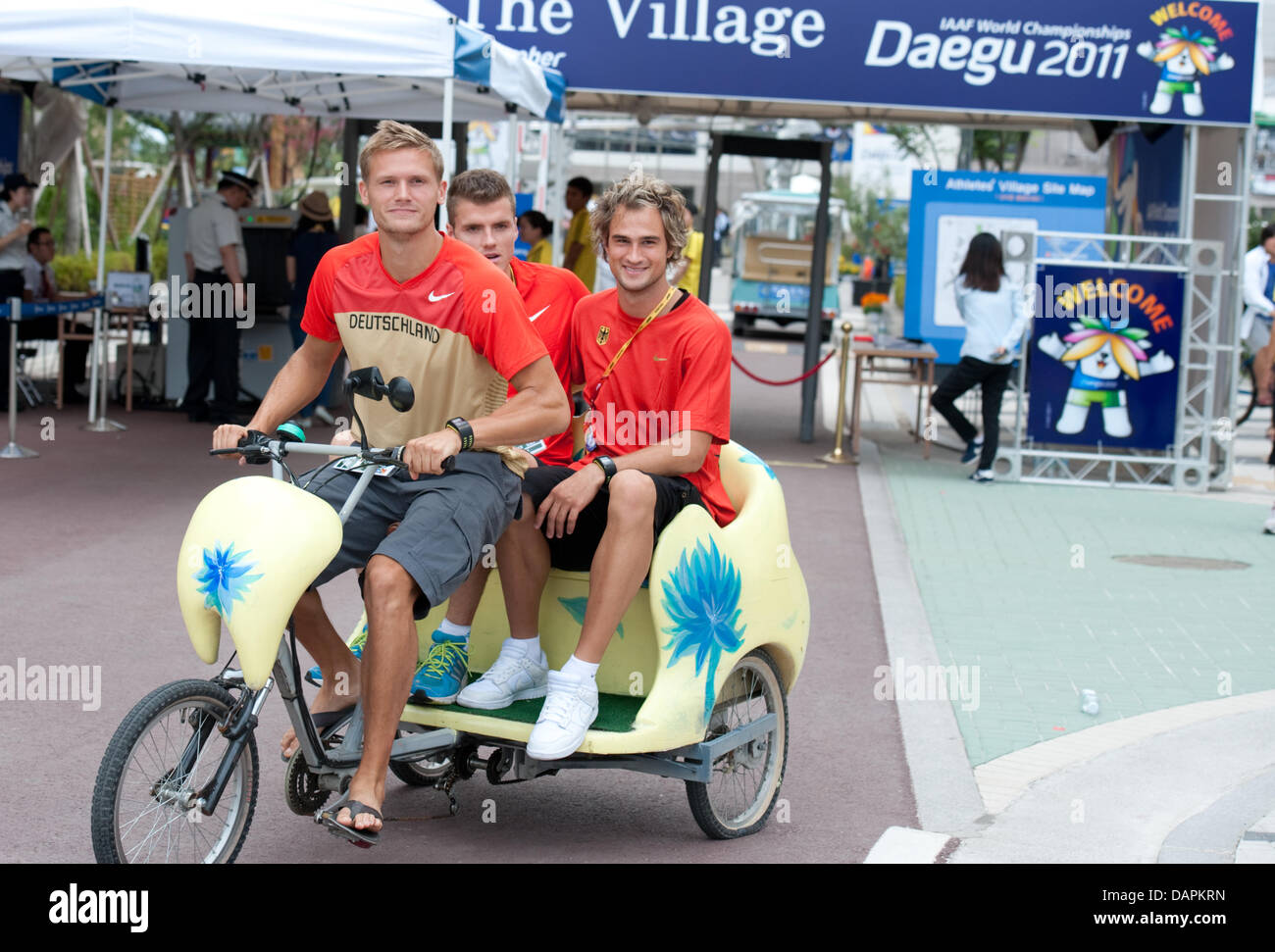 Deutsche Zehnkämpfer Pascal Behrenbruch, Rico Freimuth und Jan Felix Knobel (L-R) übernehmen eine Fahrradtour mit einer Rikscha vor den Athleten Dorf in Daegu, Südkorea, 26. August 2011. Die 2011 beginnt am 27. August 2011 IAAF World Championships. Foto: Bernd Thissen dpa Stockfoto