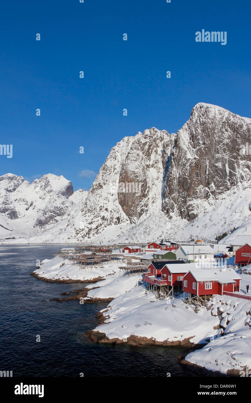 Rorbuer Kabinen und Holzgestelle mit trocknen Stockfisch bei Hamnøy / Hamnoy im Schnee im Winter, Lofoten, Nordland, Norwegen Stockfoto