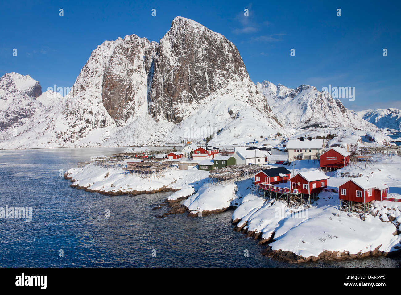 Rorbuer Kabinen und Holzgestelle mit trocknen Stockfisch bei Hamnøy / Hamnoy im Schnee im Winter, Lofoten, Nordland, Norwegen Stockfoto