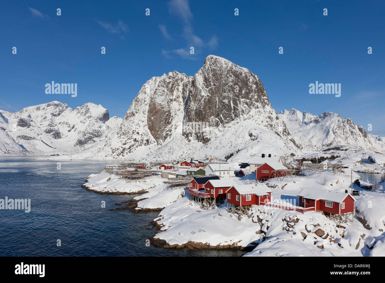 Rorbuer Kabinen und Holzgestelle mit trocknen Stockfisch bei Hamnøy / Hamnoy im Schnee im Winter, Lofoten, Nordland, Norwegen Stockfoto