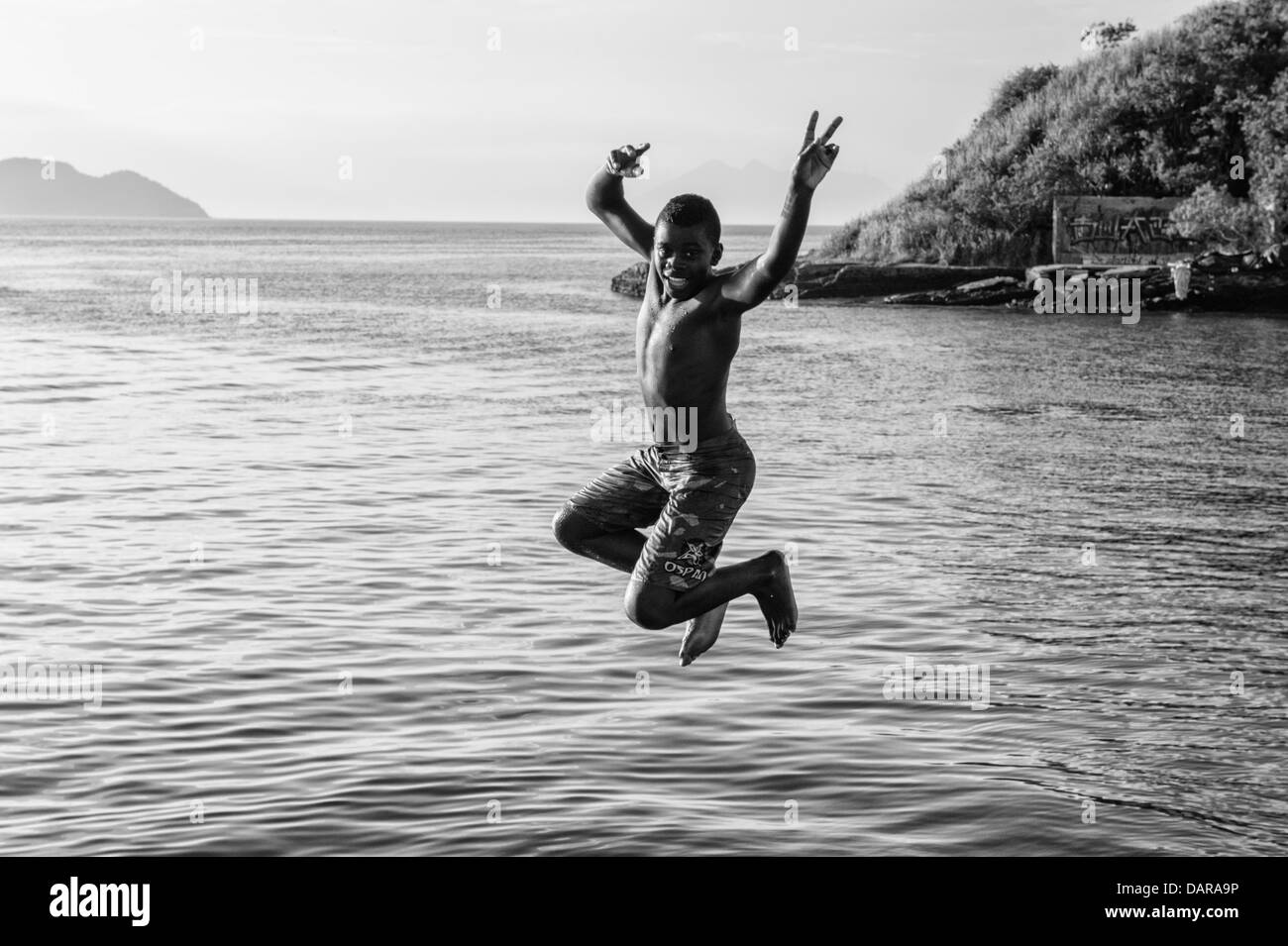 Junge, springen ins Wasser, Porto da Barra, Buzios, Rio De Janeiro, Brasilien Stockfoto
