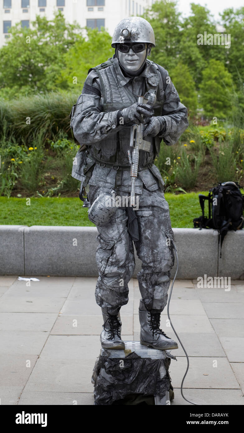 Busker Kleid in einem Armee-Kampf-Uniform und Waffe, die das Publikum unterhaltsam Stockfoto