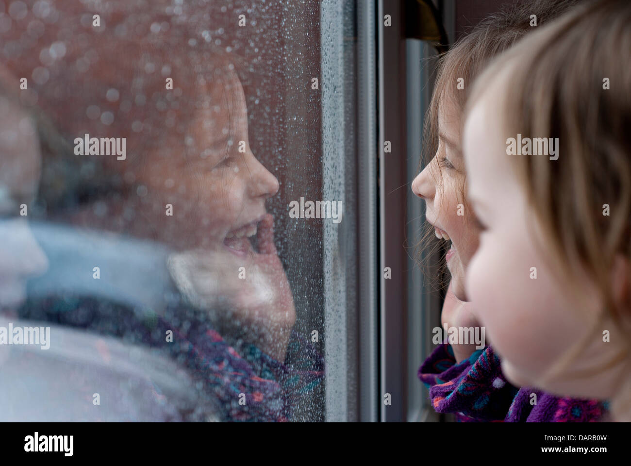 Mädchen schaut aus dem Fenster an einem regnerischen Tag Stockfoto