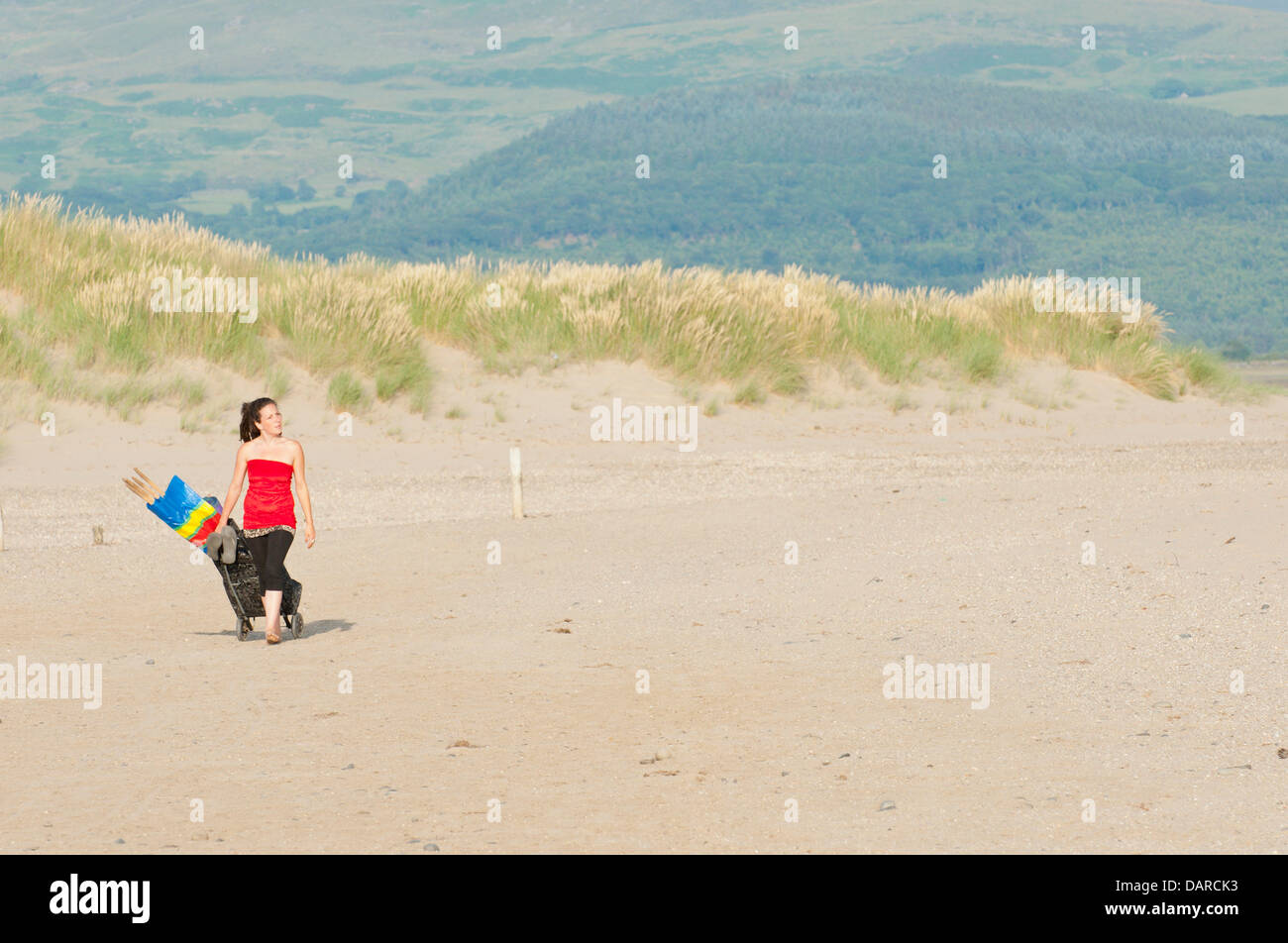 Dovey Mündung/Borth, Ceredigion, Wales, UK. 17. Juli 2013. Eine junge Frau kommt mit ihrem Buggy. Eine Ausdehnung der harten flachen Sand - die bietet einen großen Parkplatz für Autos £ 1 pro Auto pro Tag - in der Mündung des Dovey (Dyfi auf Walisisch), ist Teil eines großen Gebietes der Küstengewässer von der Landschaft Rat für Wales verfochten und zusammen mit den umliegenden Dünen bietet eine herrliche Gegend für Menschen zu entkommen, die Hitzewelle, die Großbritannien seit fast zwei Wochen glühend gewesen hat. Einladende kühle Meeresbrise bläst von der irischen See. Bildnachweis: Graham M. Lawrence/Alamy Live-Nachrichten. Stockfoto