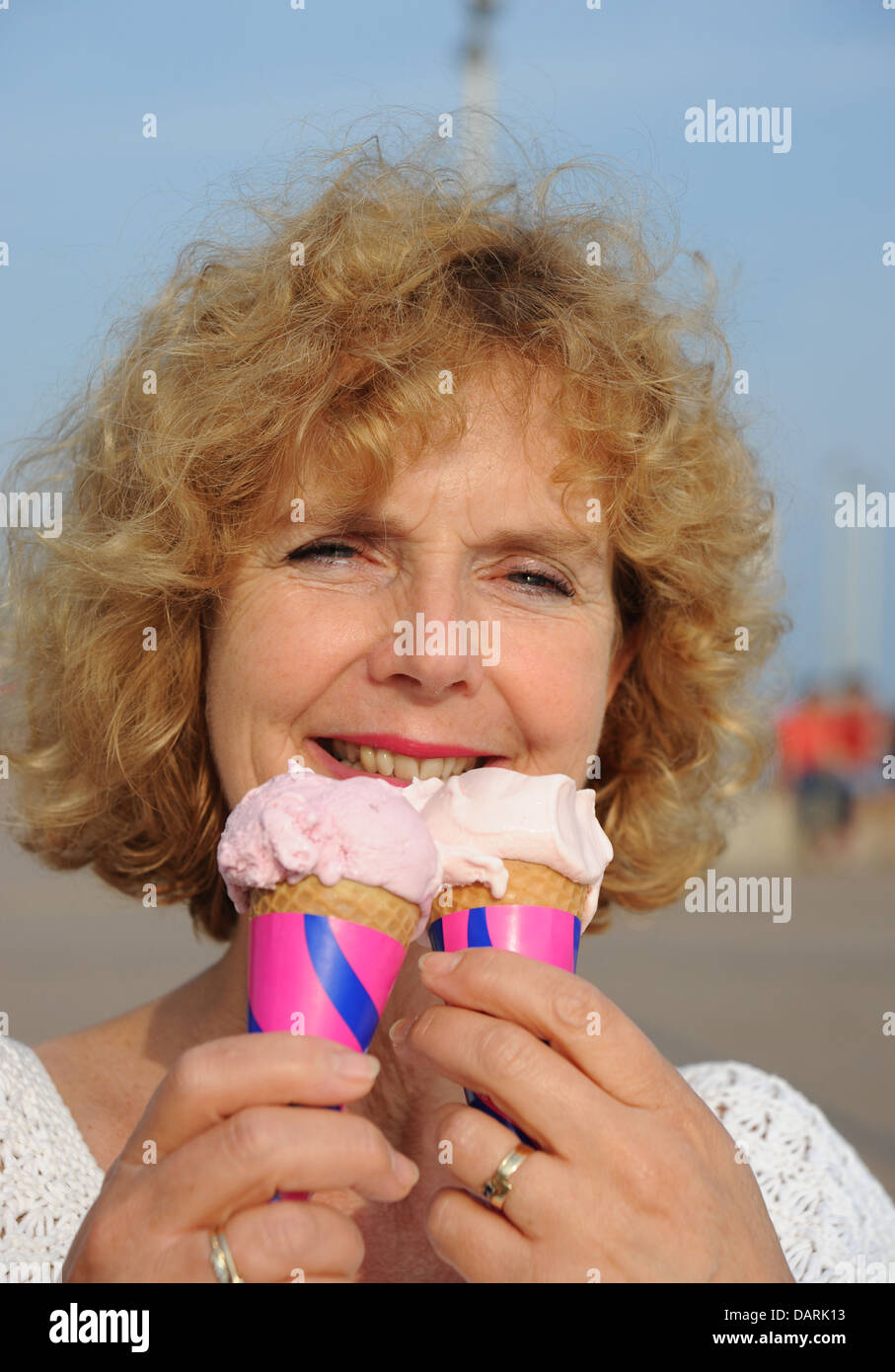 Reife mittlere gealterte Frau 50er Jahre essen Eiscreme-Kegel bei heißem Wetter Stockfoto