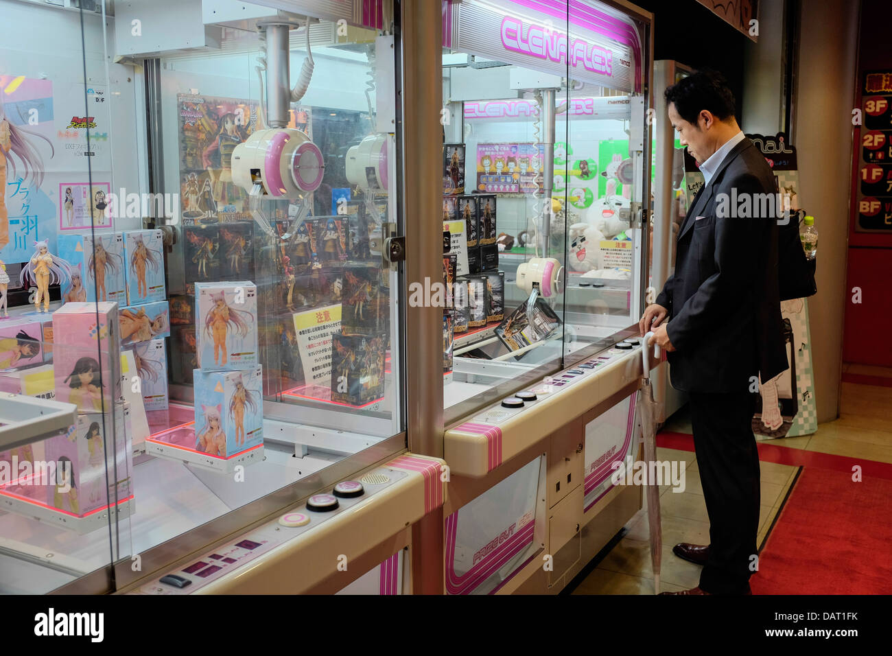 Ein japanischer Geschäftsmann spielen eine Klaue Kran Arcadespiel, Dotonburi, Osaka, Japan Stockfoto