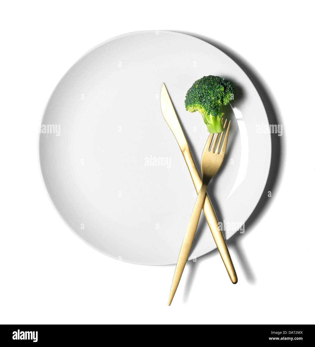weißer Teller mit Messer und Gabel und Brokkoli Stiel ausgeschnitten auf weißem Hintergrund Stockfoto