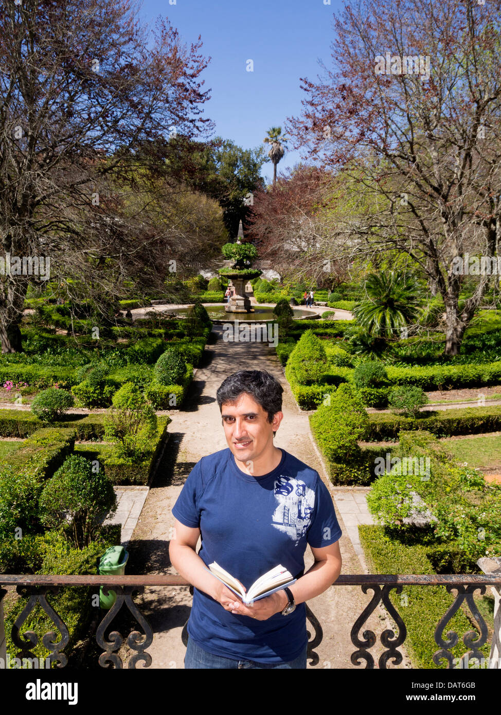 Porträt des Mannes, der ein Buch in einem Park, Blick in die Kamera hält Stockfoto