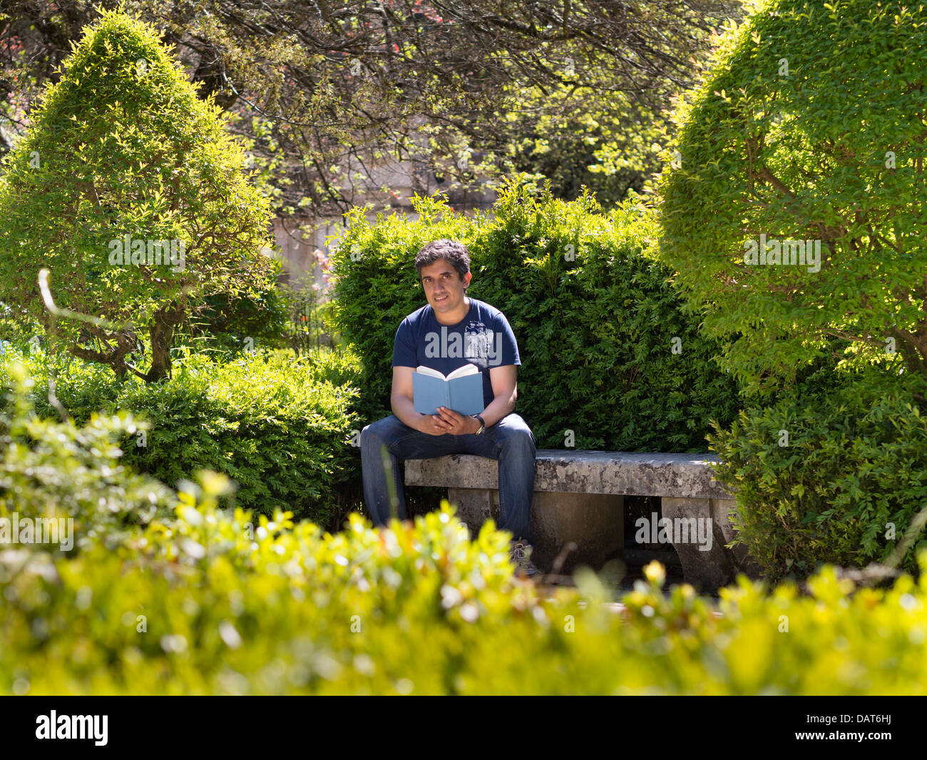 Porträt des Mannes, der ein Buch in einem Park, Blick in die Kamera hält Stockfoto