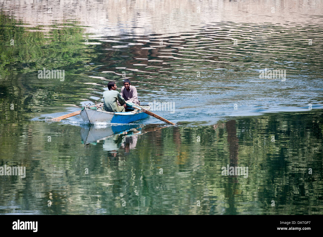 Nils Fischer in kleines Ruderboot mit Flussufer spiegelt sich im Plätschern des Wassers Stockfoto