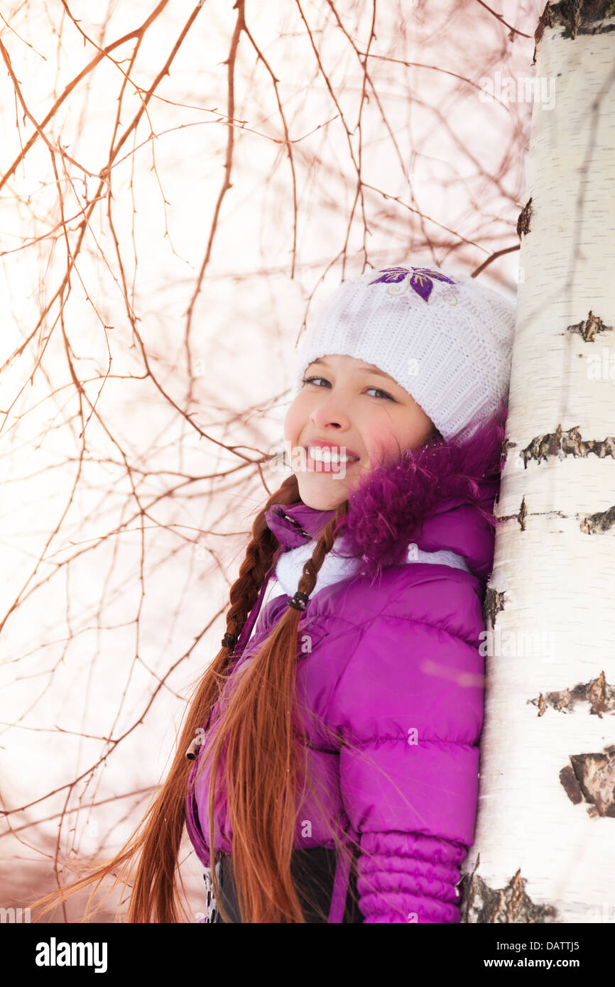 Niedliche kleine Mädchen umarmt He Birke auf Schnee Wintertag Stockfoto