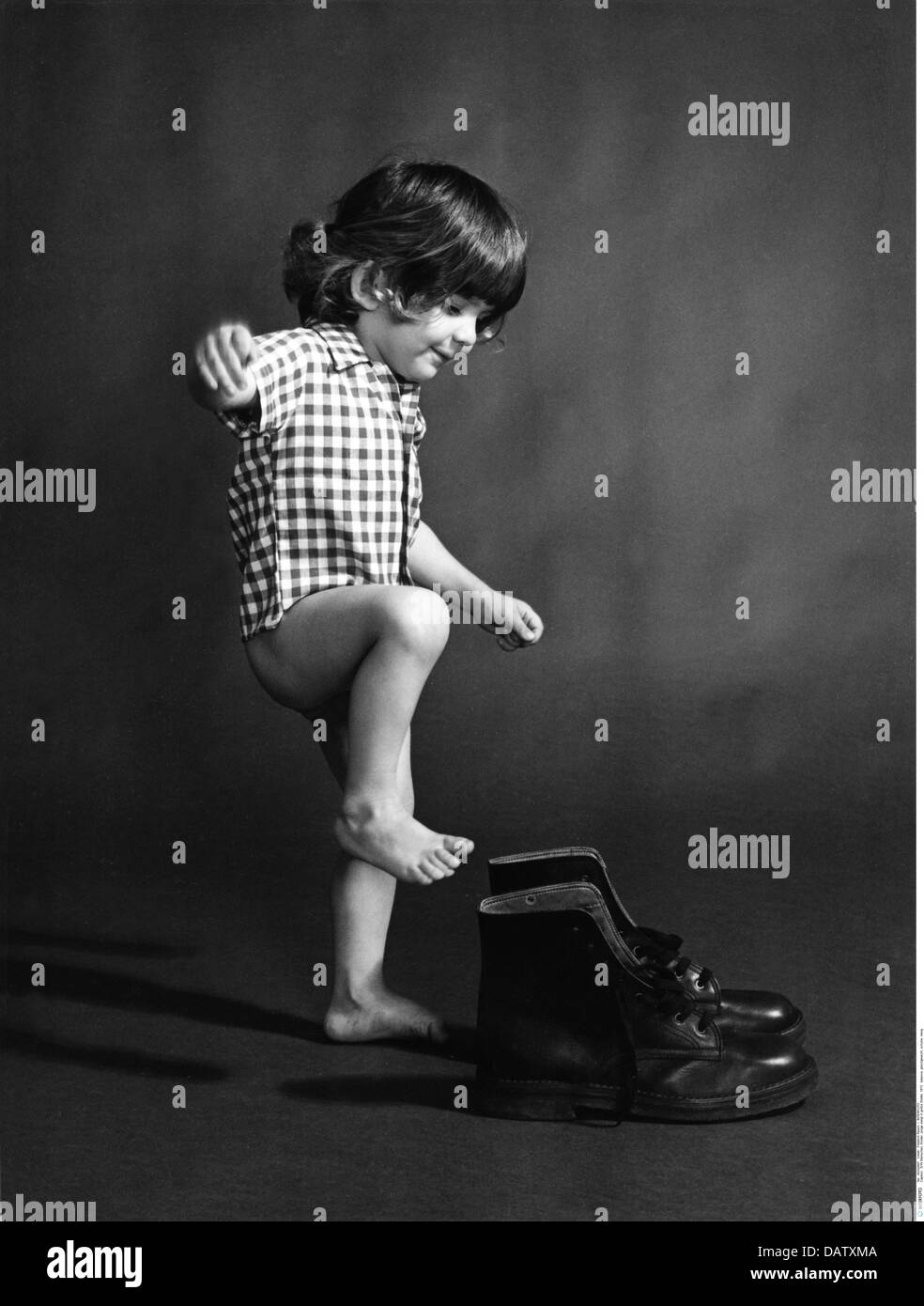 Personen, Kinder, Kleinkinder (bis 5 Jahre), Junge versucht, in große Stiefel zu bekommen, 1973, zusätzliche-Rechte-Clearences-nicht verfügbar Stockfoto