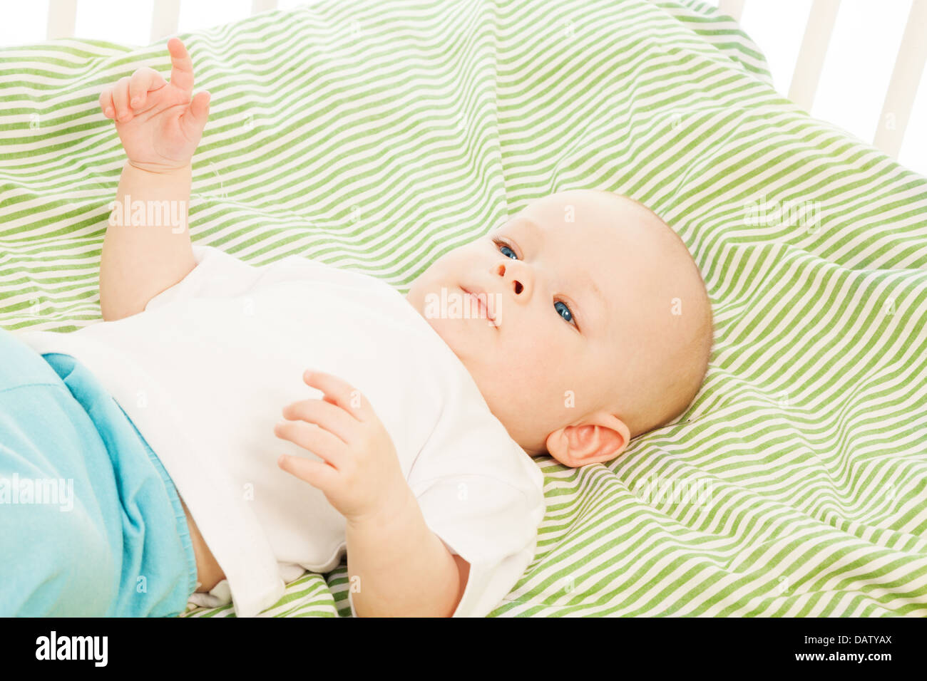 Ruhige kleine 6 Monate junge Verlegung in seinem Bettchen und deutete auf Mama Stockfoto