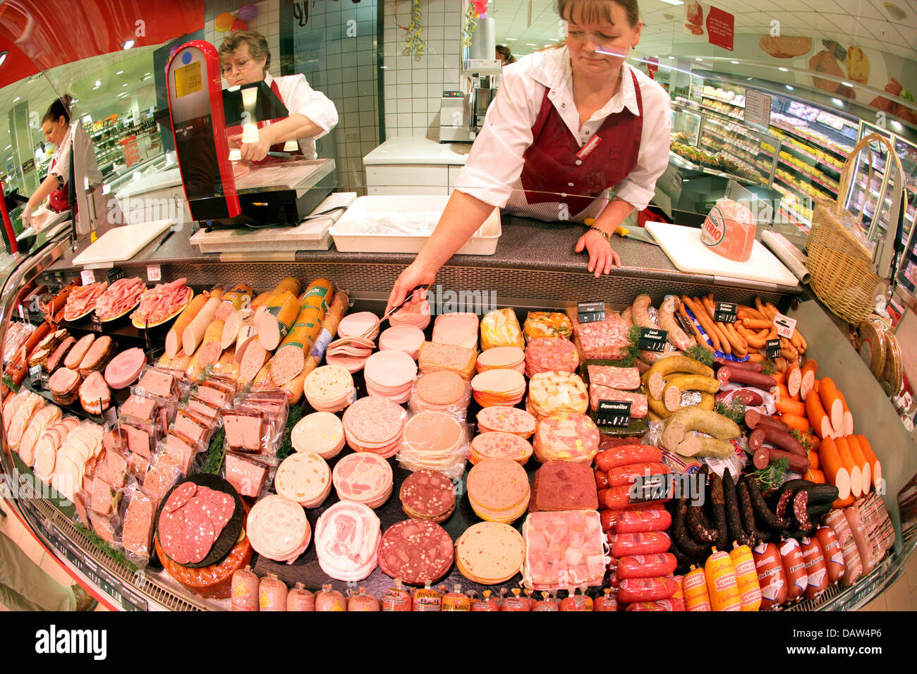 Ein Mitarbeiter organisiert verschiedene Arten von Wurst in einem gekühlten Regal in einem umgebauten REWE Supermarkt Laden in Köln, Deutschland, 19. Januar 2007. Foto: Rolf Vennenbernd Stockfoto