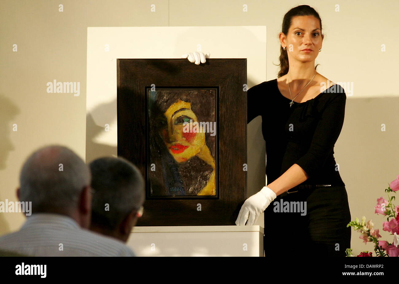 Ein weibliches Mitglied des Personals der Auktionatoren "Ketterer Kunst"  präsentiert das Gemälde "Nadja" von Emil Nolde (1919) während der Auktion  am 'Prinzregententheater' in München, Deutschland, 12. Juni 2007. Das  Gemälde nach Verlorenheit