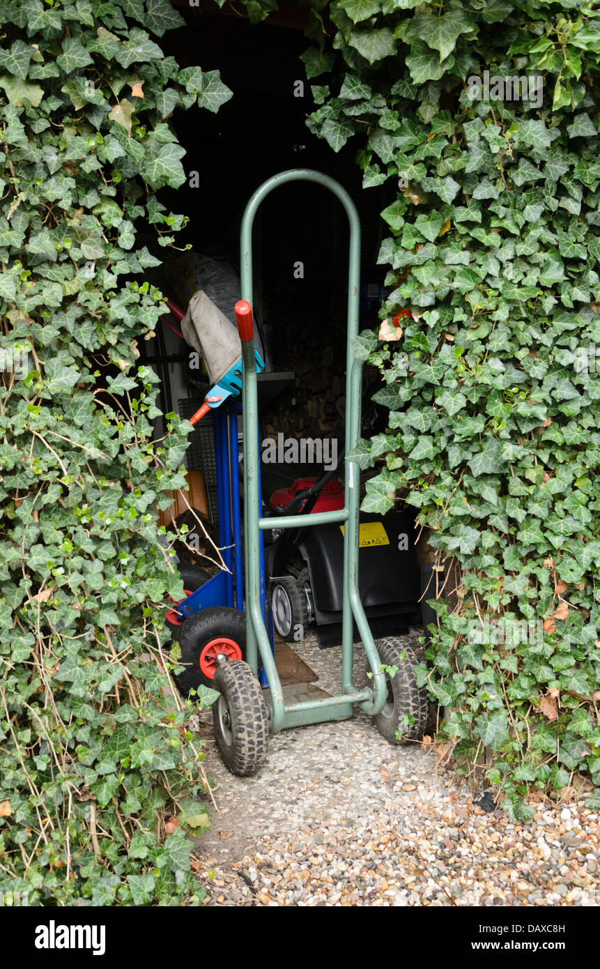 Im Garten arbeitende Werkzeuge in einem Efeu bewachsenen vergossen Stockfoto