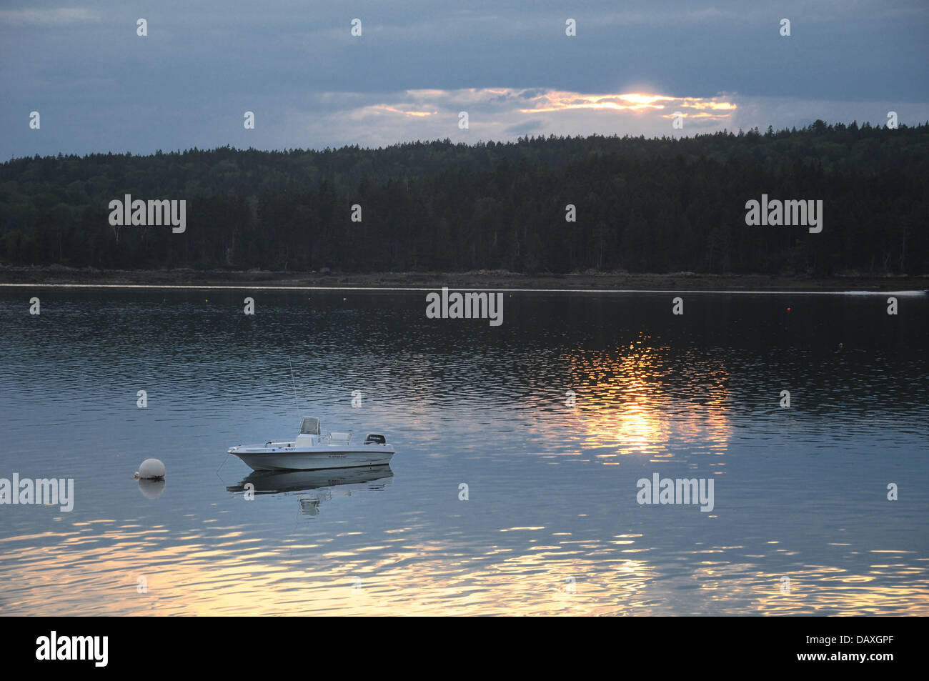Ein kleines Motorboot vertäut off Shore mit reflektierenden Sonnenuntergang im Wasser Stockfoto