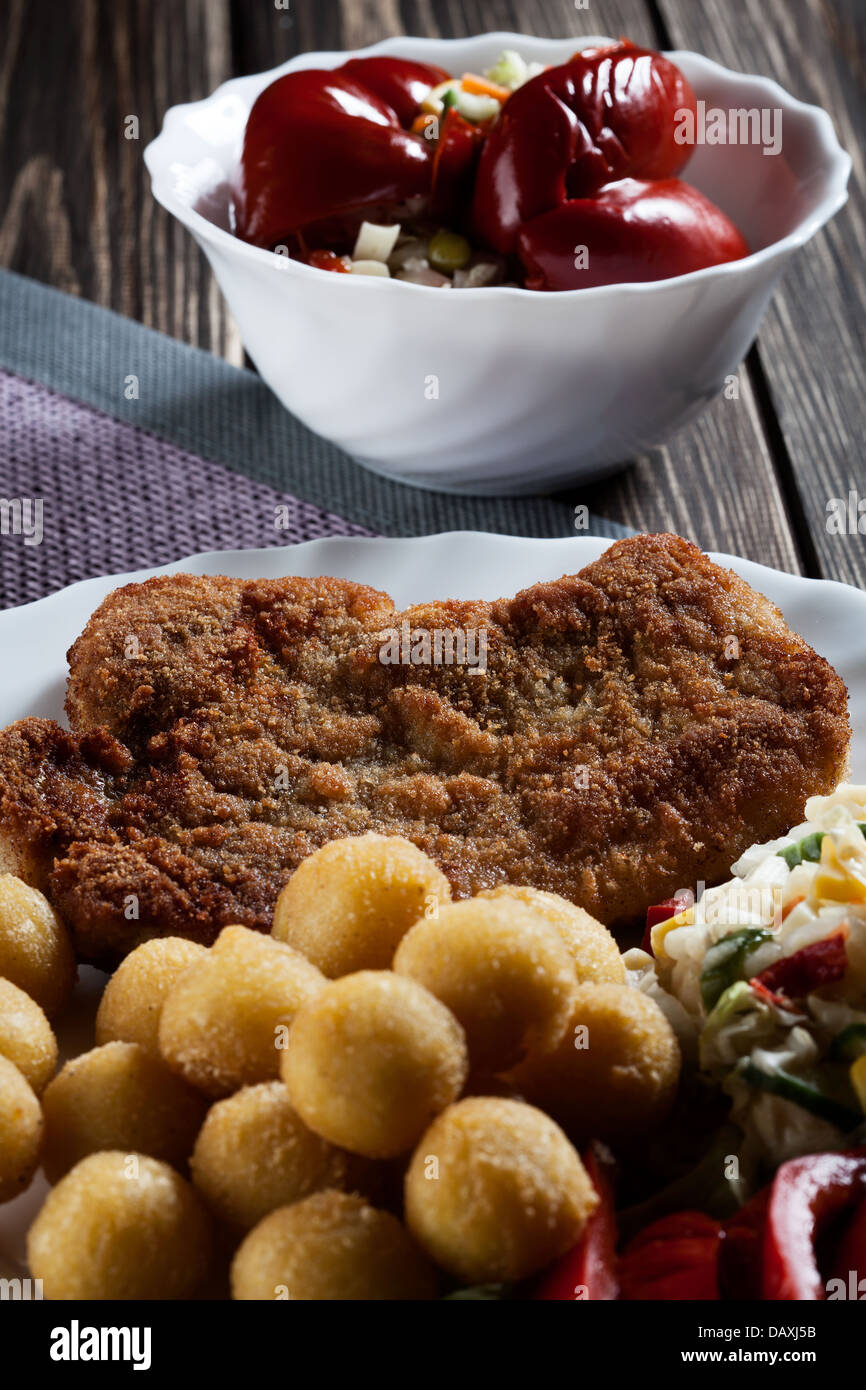 Paniertes Kotelett, Kartoffeln und Salat zubereitet. Geheimnisvolles Licht Stockfoto
