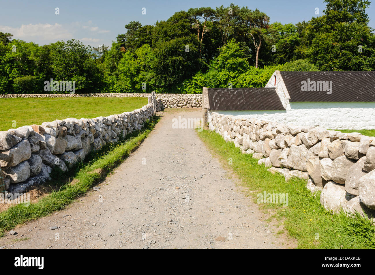 Trockenmauern führen hinunter zu einem weiß getünchten irischen Bauernhaus Stockfoto